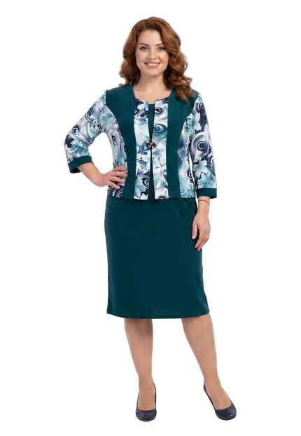 Цял ръст на жена в официална масленозелена рокля с флорални мотиви на бял фон.