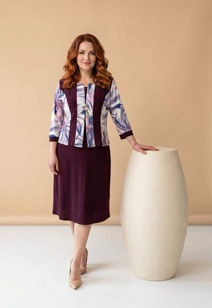 Кадър в цял ръст на официална права макси рокля в бордо. Моделът се отличава с абстрактен принт, 3/4 ръкави и стилна декоративна брошка.