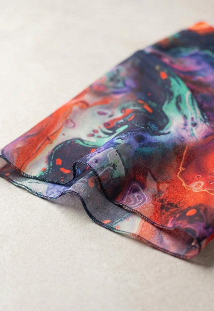 Детайл отблизо на късия разкроен ръкав от пъстър шифон с ярък абстрактен принт на официална рокля големи размери.