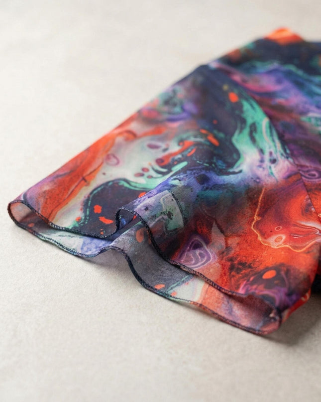 Детайл отблизо на късия разкроен ръкав от пъстър шифон с ярък абстрактен принт на официална рокля големи размери.