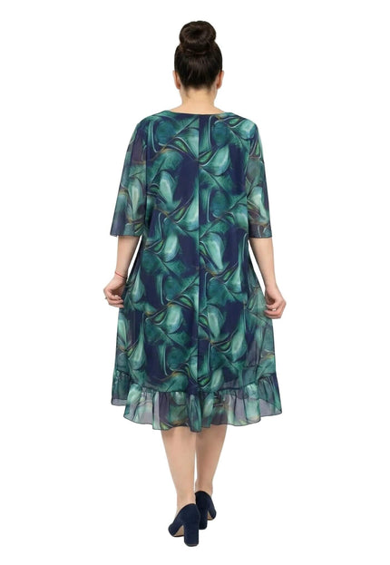 Официална шифонена рокля големи размери в преливащи сини тонове, заснета отзад в цял ръст на бял фон, показваща широките ръкави и волана на подгъва.