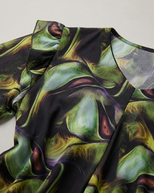 Детайлен кадър на официална шифонена рокля с пъстър абстрактен десен, показващ V-образното деколте, ефирната материя и къдрите на ръкавите.