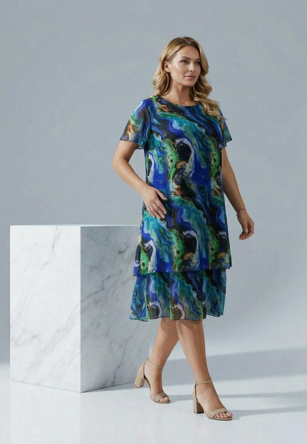 Официална шифонена рокля в преливащи тонове големи размери, моделът е сниман в цял ръст до мраморен куб.