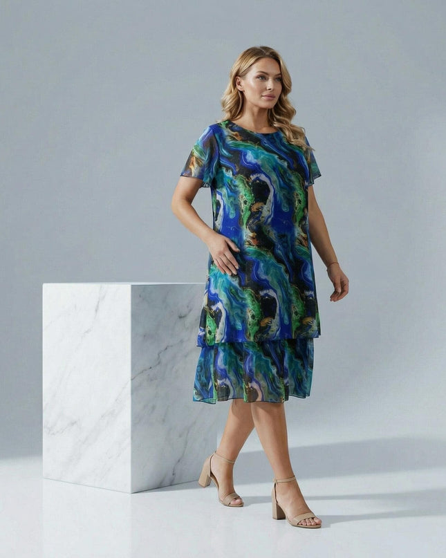 Официална шифонена рокля в преливащи тонове големи размери, моделът е сниман в цял ръст до мраморен куб.