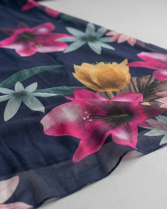 Детайл отблизо на тъмносиня макси рокля, показващ ефирния шифон с ярък флорален принт в розови и жълти нюанси.