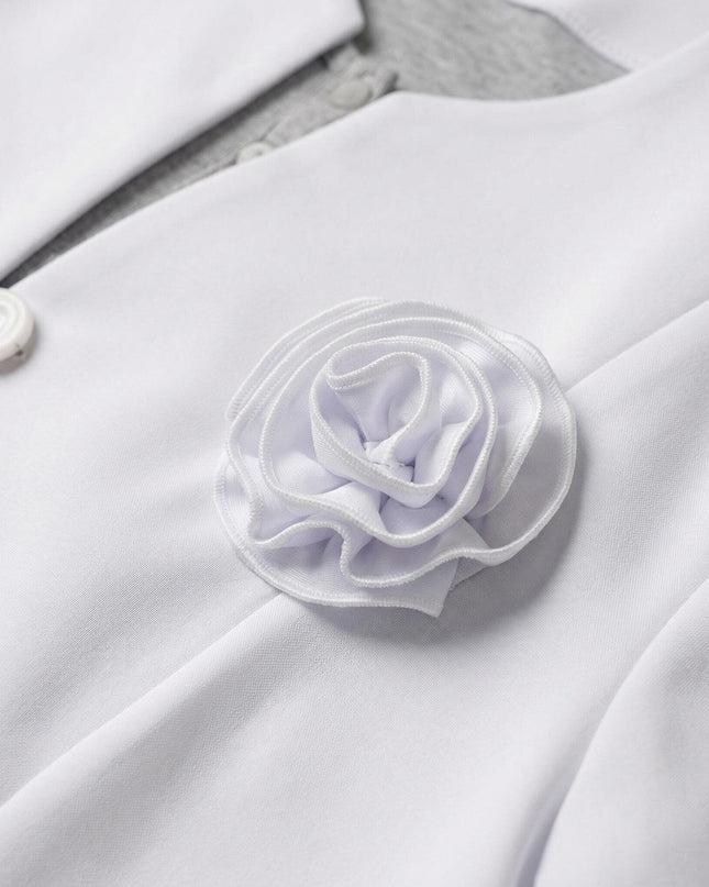 Детайл отблизо на официално бяло сако, акцентиращ върху красивата текстилна роза и класическото закопчаване с копче.