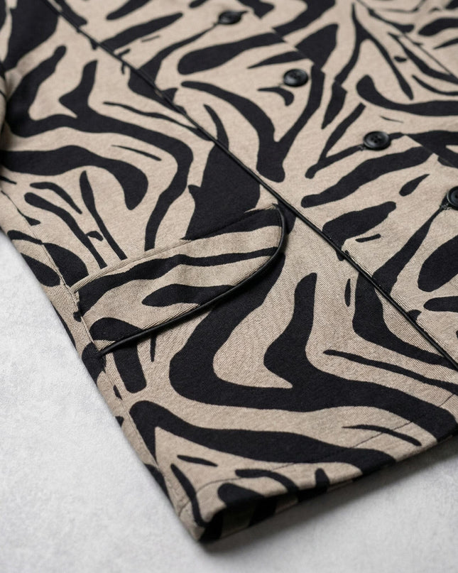 Детайлен поглед към материята, копчетата и джоба на официално дамско макси сако в бежово с ефектен черен десен.