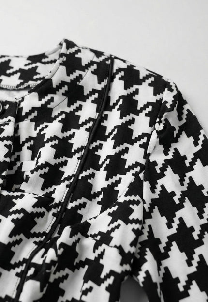 Близък план на официално дамско сако пепит в бяло, показващ детайли на яката, черните копчета и текстурата на материята.