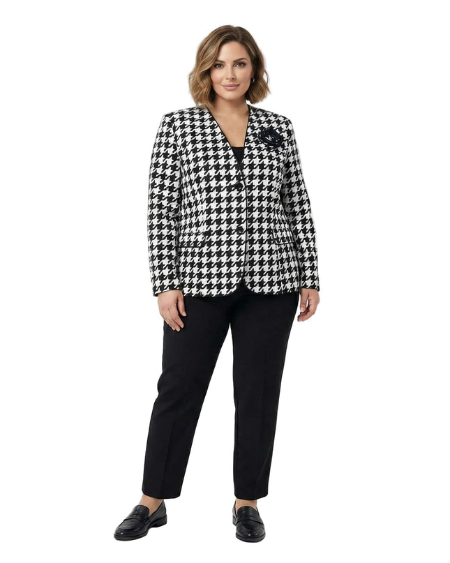 Официално дамско сако в черно-бял пепит с декоративна роза и черен кант, представено в цял ръст върху модел с черен панталон.