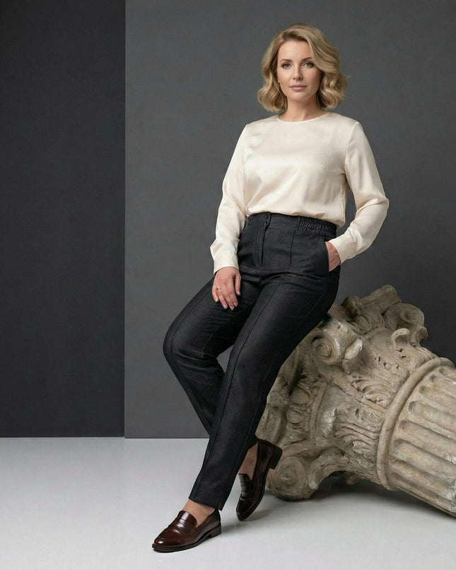 Официален дамски черен панталон с прав крачол за големи размери. Моделът е сниман в седнала поза върху декоративна колона, подчертаваща елегантния силует.