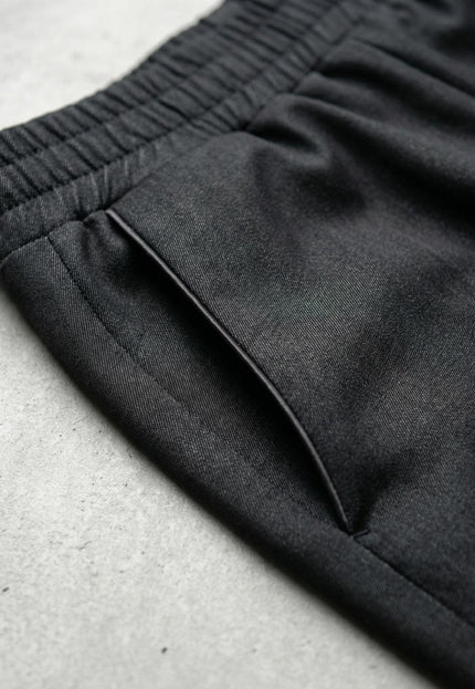 Детайл отблизо на страничен джоб и ластик на талията на официален дамски черен панталон, показващ текстурата на плата.