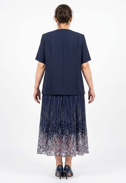 Официален дамски комплект в тъмносиньо, състоящ се от сако с къс ръкав и пола с флорални мотиви. Изглед отзад на модела.