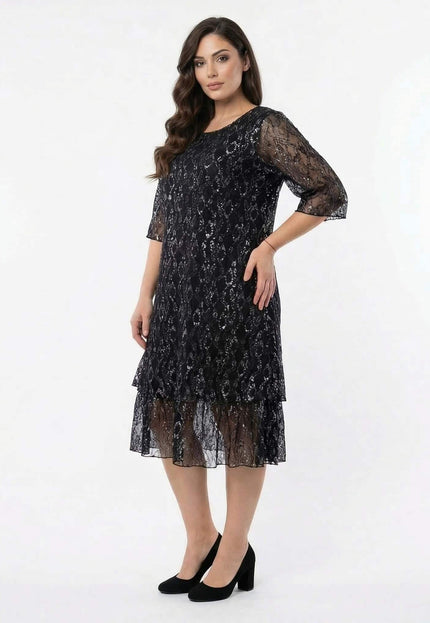 Официална черна макси рокля с флорална дантела, 3/4 прозрачни ръкави и етажиран подгъв, кадър в цял ръст.