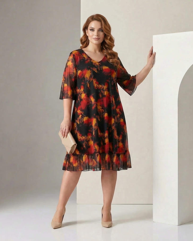 Цял ръст на модел, носещ официална черна макси рокля с шифон и абстрактен огнен принт, допълнена с волан на подгъва.