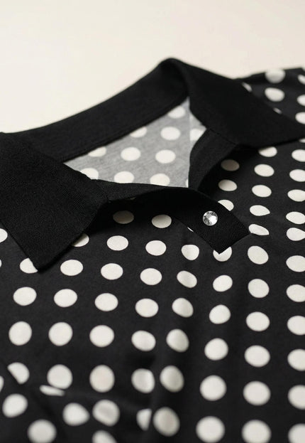 Детайл отблизо на черна макси туника, показващ елегантната яка, прозрачното декоративно копче и десена на бели точки.