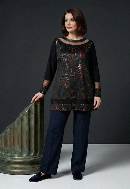 Елегантна черна туника големи размери с абстрактни мотиви и прозрачни елементи, представена в цял ръст до декоративна колона