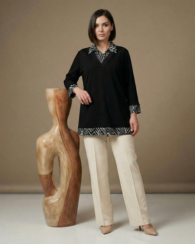 Официална черна туника с яка и маншети на геометрични фигури, заснета в цял ръст до декоративна скулптура.