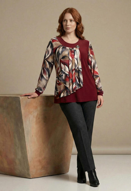 Официална червена туника с флорален шифон и брошка, представена в цял ръст върху модел до интериорен елемент.