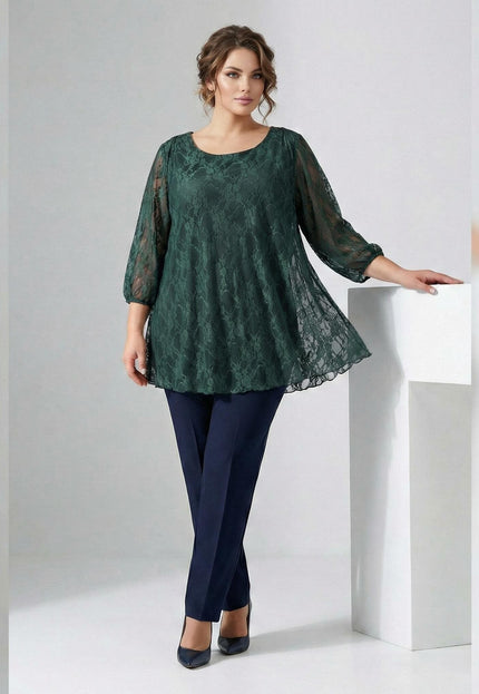 Официална дантелена туника в масленозелен цвят за макси дами, представена в цял ръст. Елегантен модел с флорални мотиви, разкроена кройка и прозрачни 7/8 ръкави.