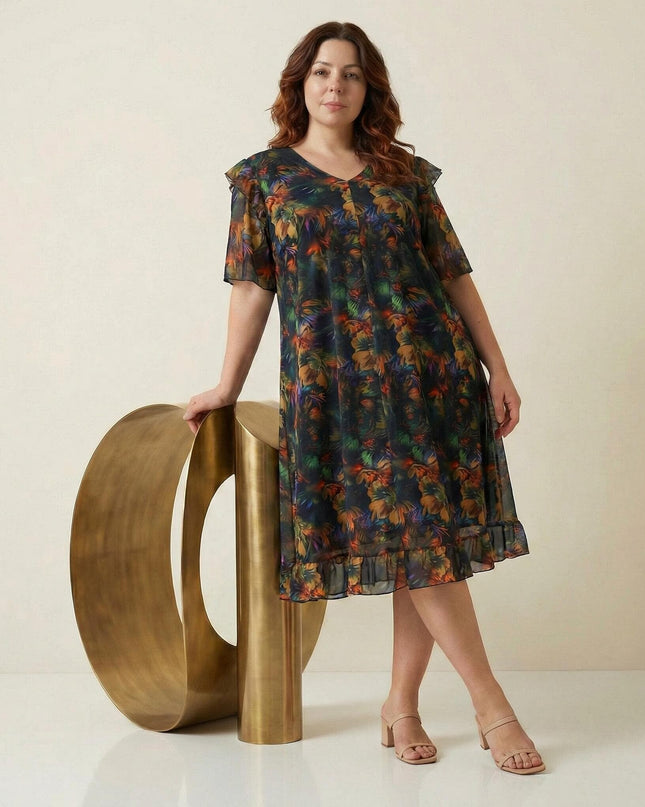 Официална макси рокля от цветен шифон с ефектен ръкав и флорален десен, представена в цял ръст до златист декоративен елемент.