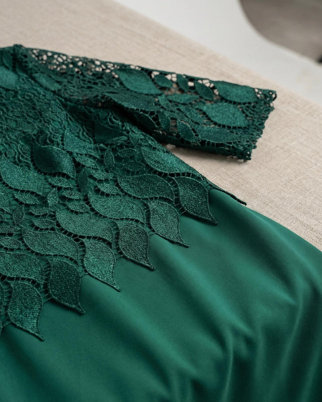 Детайлен кадър на официална макси рокля в масленозелен цвят, показващ отблизо красивата дантела с мотиви на листа в горната част.