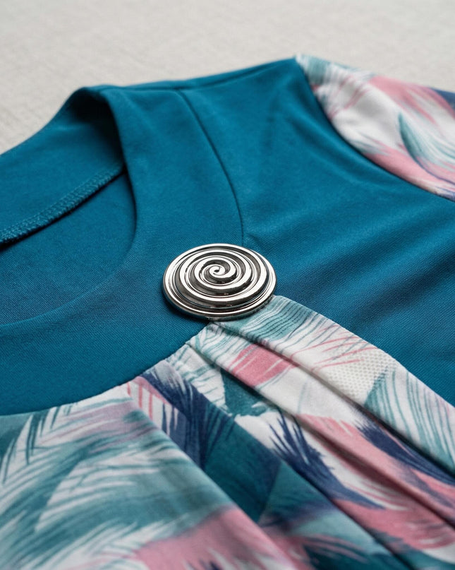 Детайл отблизо на деколте с елегантна сребриста брошка върху официална макси туника в цвят петрол и цветен ефирен шифон.