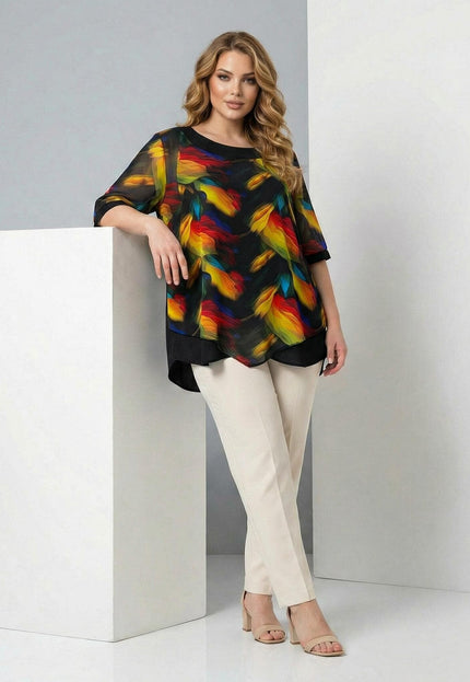 Официална макси туника в черно с асиметричен слой от пъстър шифон и абстрактен десен, представена в цял ръст върху модел до бял декор.