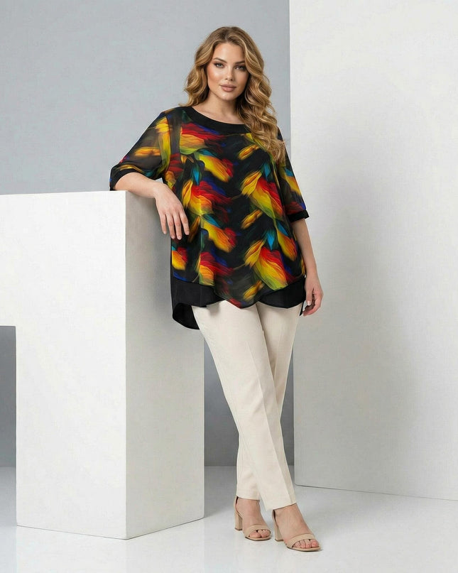 Официална макси туника в черно с асиметричен слой от пъстър шифон и абстрактен десен, представена в цял ръст върху модел до бял декор.
