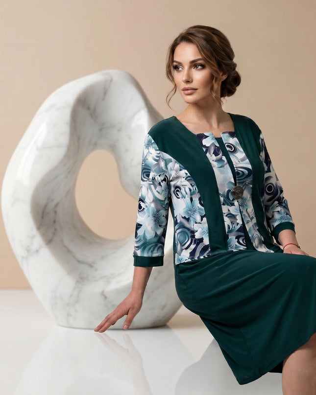 Официална масленозелена рокля големи размери с флорални мотиви. 3/4 кадър, показващ елегантния ефект от две части и декоративната брошка на деколтето.