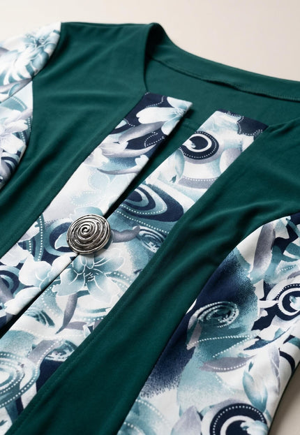 Детайл отблизо на официална масленозелена рокля, показващ красивите флорални мотиви и изящната декоративна метална брошка.