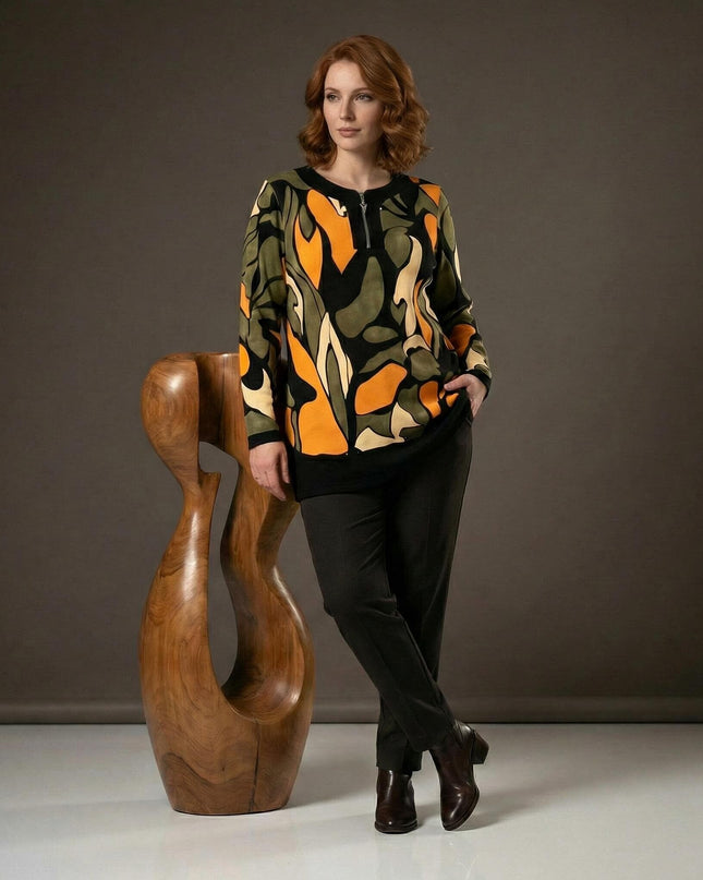 Официална разкроена макси туника с цип в шарен десен, представена върху модел в цял ръст до декоративна дървена фигура.