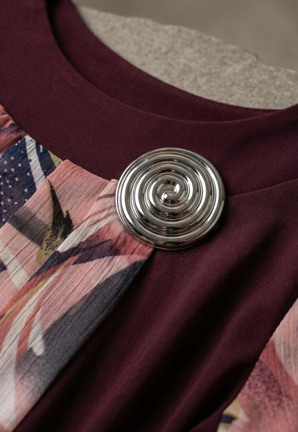 Детайл отблизо на сребриста брошка и деколте на официална макси туника в бордо, комбинирана с цветен шифон.