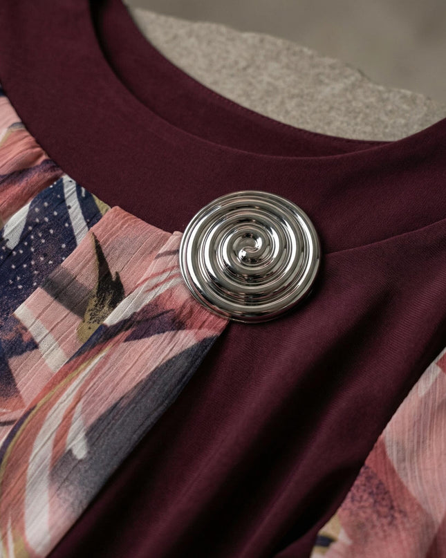 Детайл отблизо на сребриста брошка и деколте на официална макси туника в бордо, комбинирана с цветен шифон.
