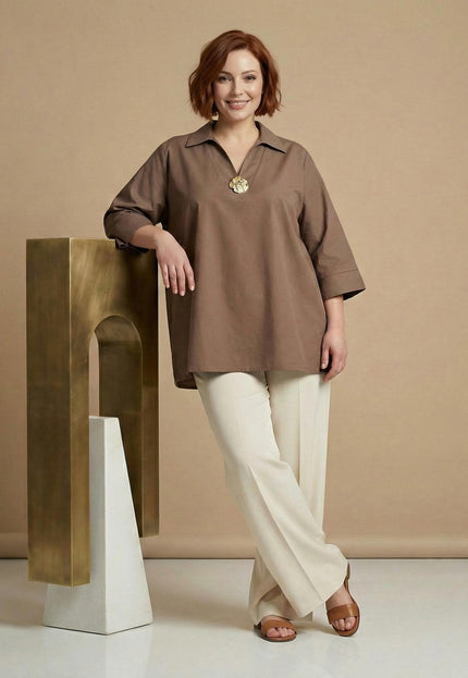 Елегантна разкроена памучна макси риза в цвят мока с декоративен елемент на деколтето, представена в цял ръст върху модел до златист постамент