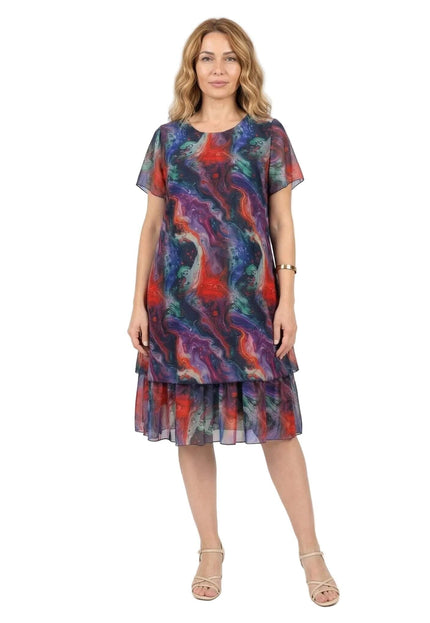 Официална разкроена рокля големи размери от пъстър шифон. Снимка в цял ръст на бял фон, показваща многопластовия дизайн и абстрактния принт.