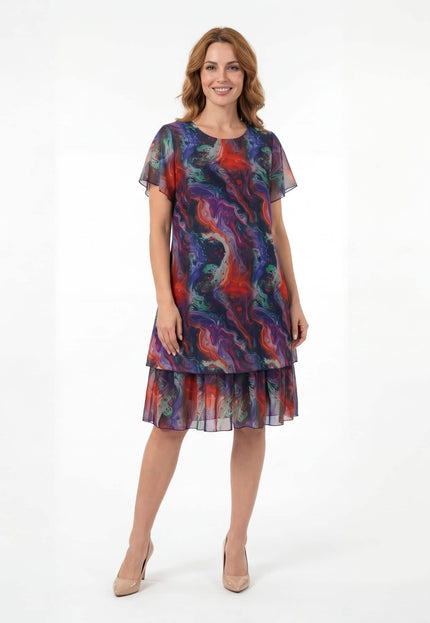 Официална разкроена рокля големи размери от пъстър шифон с къси ръкави, снимана в цял ръст на бял фон.