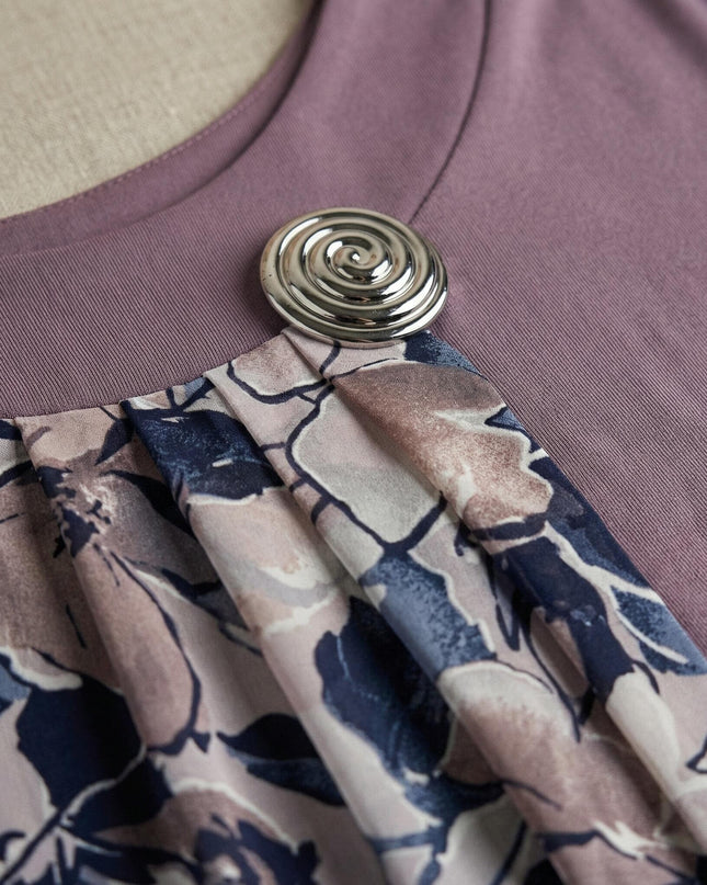 Детайлен кадър на деколтето на официална туника в цвят пепел от рози, акцентиращ върху елегантната сребриста брошка и набрания флорален шифон.