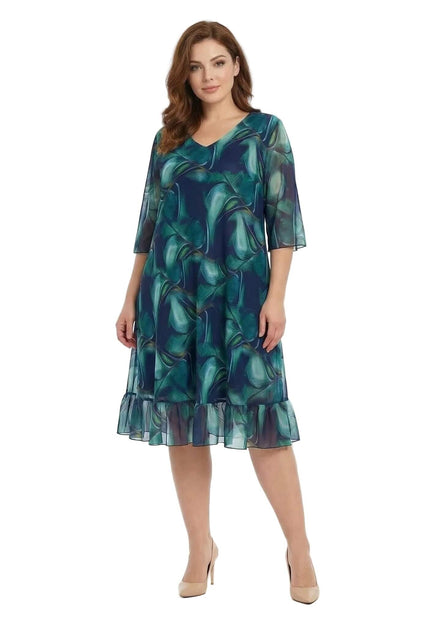 Официална шифонена рокля големи размери в преливащи сини тонове с V-образно деколте и подгъв с волан, заснета отпред в цял ръст на бял фон.