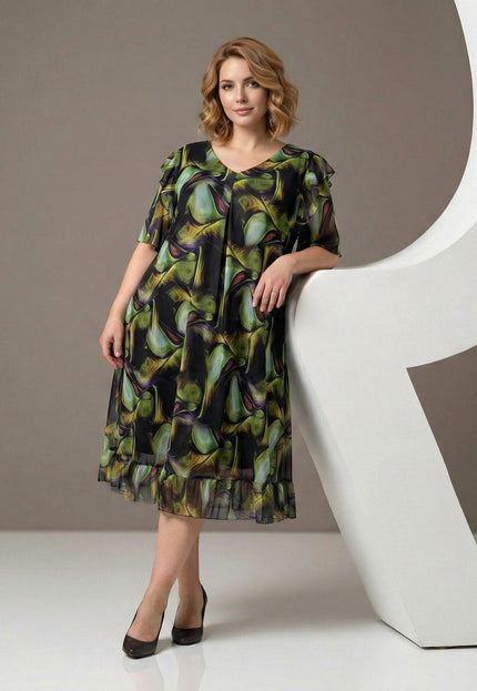 Официална шифонена рокля в пъстър десен с разкроена кройка и ефирни волани, представена върху модел в цял ръст до бял декор.