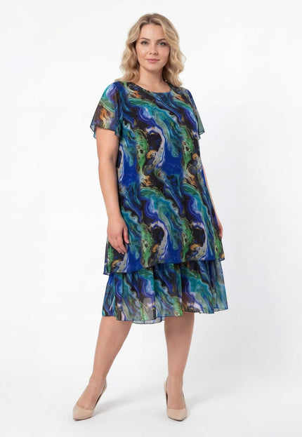 Официална шифонена рокля в преливащи тонове големи размери, заснета в цял ръст на бял фон, показваща разкроената кройка и многопластовия дизайн.