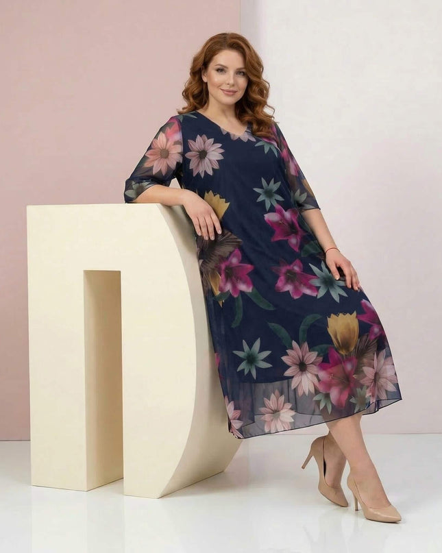 Официална тъмносиня макси рокля с ефирен флорален шифон. Кадър в цял ръст на модел, демонстриращ елегантната разкроена кройка и 3/4 ръкави.