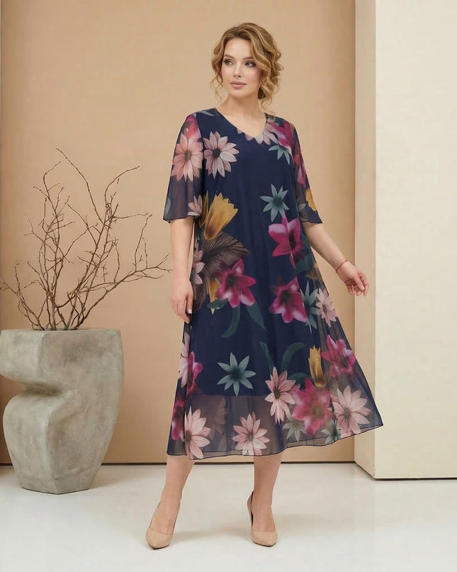 Официална тъмносиня макси рокля от ефирен шифон с едър флорален принт. Кадър в цял ръст, демонстриращ разкроената кройка и V-образното деколте.