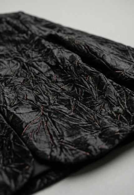 Детайл отблизо на текстурата на официално дамско макси сако, изработено от черен релефен велур с ефектен дизайн.