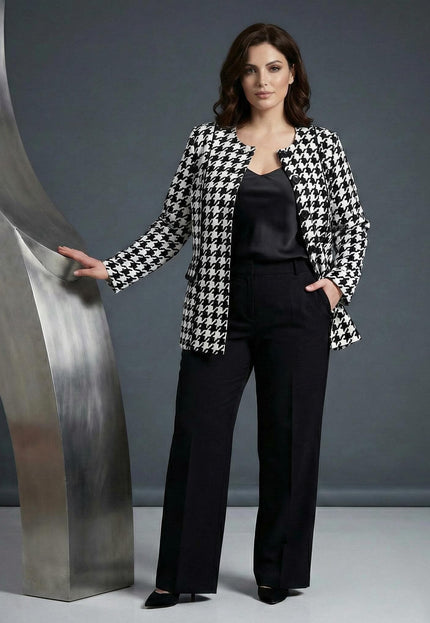 Официално дамско сако пепит в бяло големи размери, заснето в цял ръст върху модел с черен панталон.