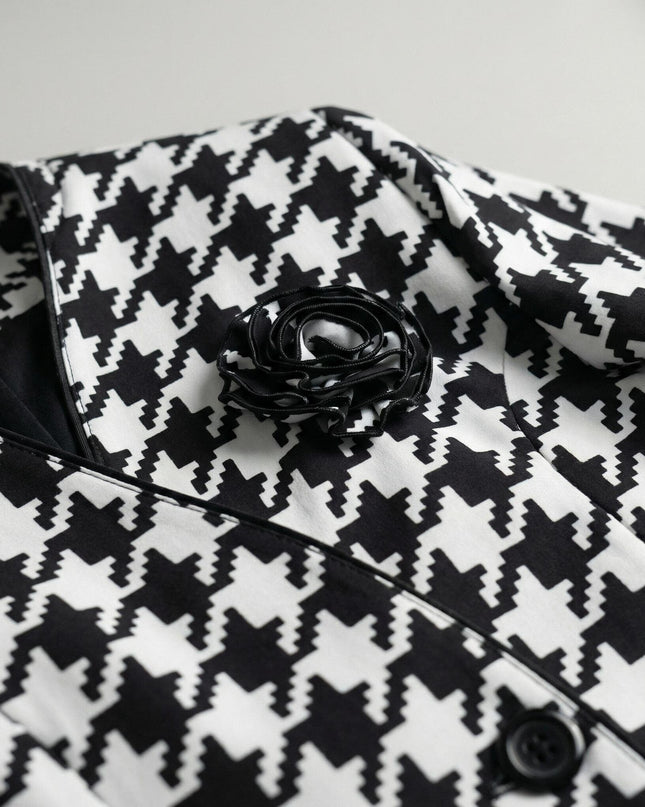 Детайлен кадър на официално дамско сако в пепит, показващ отблизо декоративната черна роза, яката с кант и текстурата на материята.