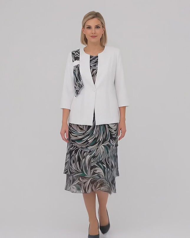 Видео в студио с неутрален фон, на което плюс сайз жена модел върви бавно към камерата, облечена в Официален дамски костюм от две части с шарена шифонена рокля големи размери