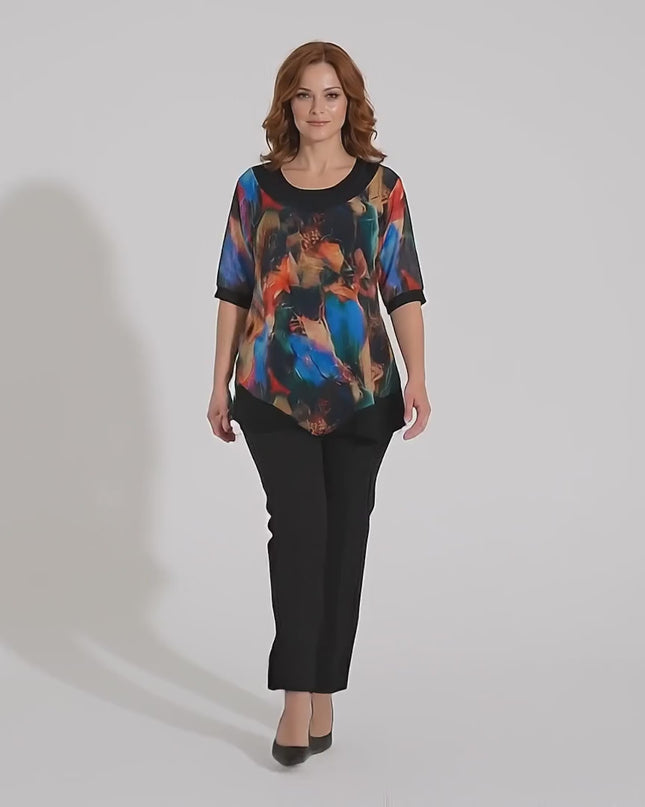 Видео в студийна среда, показващо плюс сайз модел, който върви бавно към камерата, облечен в Официална разкроена туника с асиметричен шифон и цветен принт