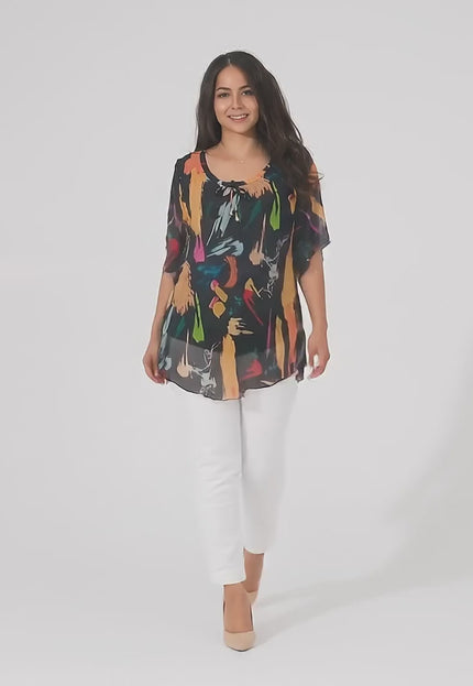 Видео в студийна среда на неутрален фон, в което плюс сайз модел носи Черна шифонена туника в големи размери с абстрактен десен и върви бавно към камерата