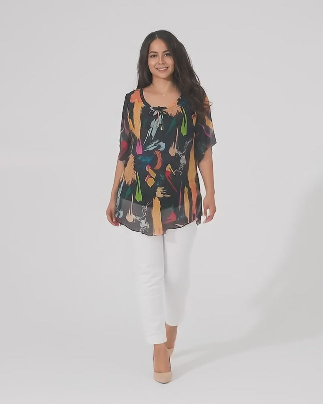 Видео в студийна среда на неутрален фон, в което плюс сайз модел носи Черна шифонена туника в големи размери с абстрактен десен и върви бавно към камерата