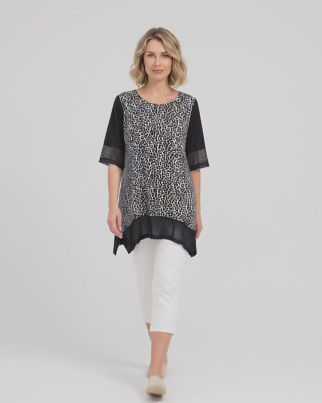 Плюс сайз модел е облечен в Черна лятна макси туника от памук с елементи от мрежа и върви бавно към камерата в студийна среда на неутрален фон